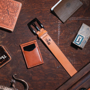 Tan Leather belt and matching wallet on a wooden surface with decorative elements.