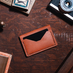 Everyday bifold Solid Leather wallet in tan leather on a dark wooden desk. Handmade in Peterborough Ontario by Jesse Bateson