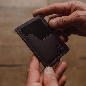 a dark brown Solid Leather minimalist wallet being held by a mans hands and a blurred background