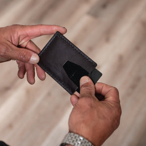a pair of mans hands holds a dark brown full grain leather cardholder wallet