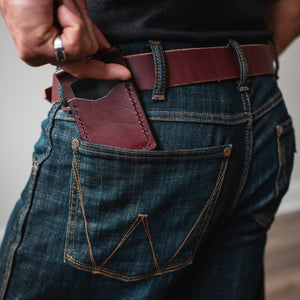full-grain burgundy leather wallet in the back pocket of blue jeans with a matching full-grain leather belt
