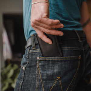 hands taking a black leather bifold wallet out of the back pocket of jeasn with a matching Solid Leather belt