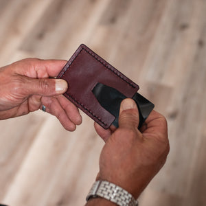 hands holding a full-grain burgundy leather cardholder wallet with blurred background 