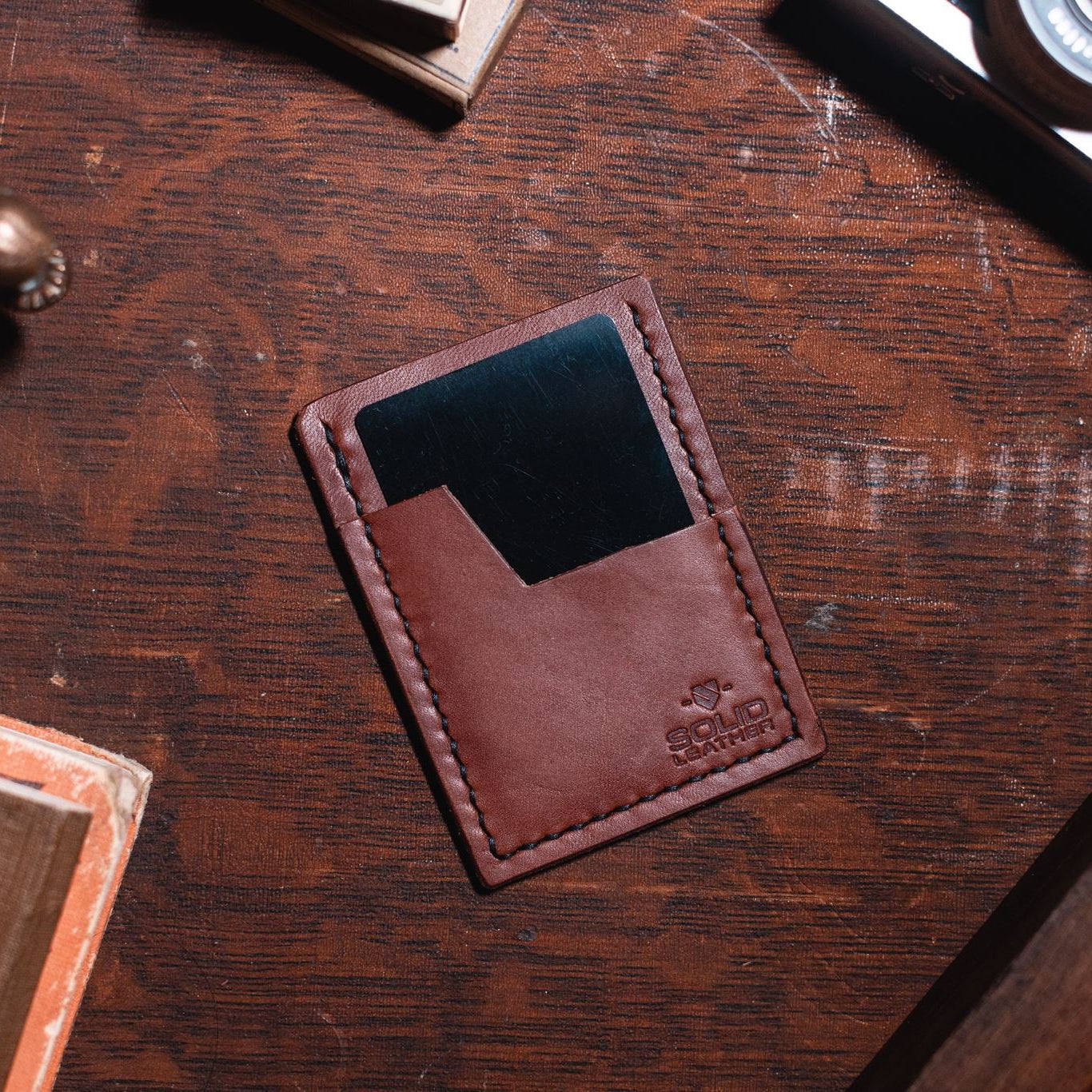 Solid Leather cognac brown minimalist cardholder wallet on a dark wood desk. Handmade in Peterborough Ontario Canada 