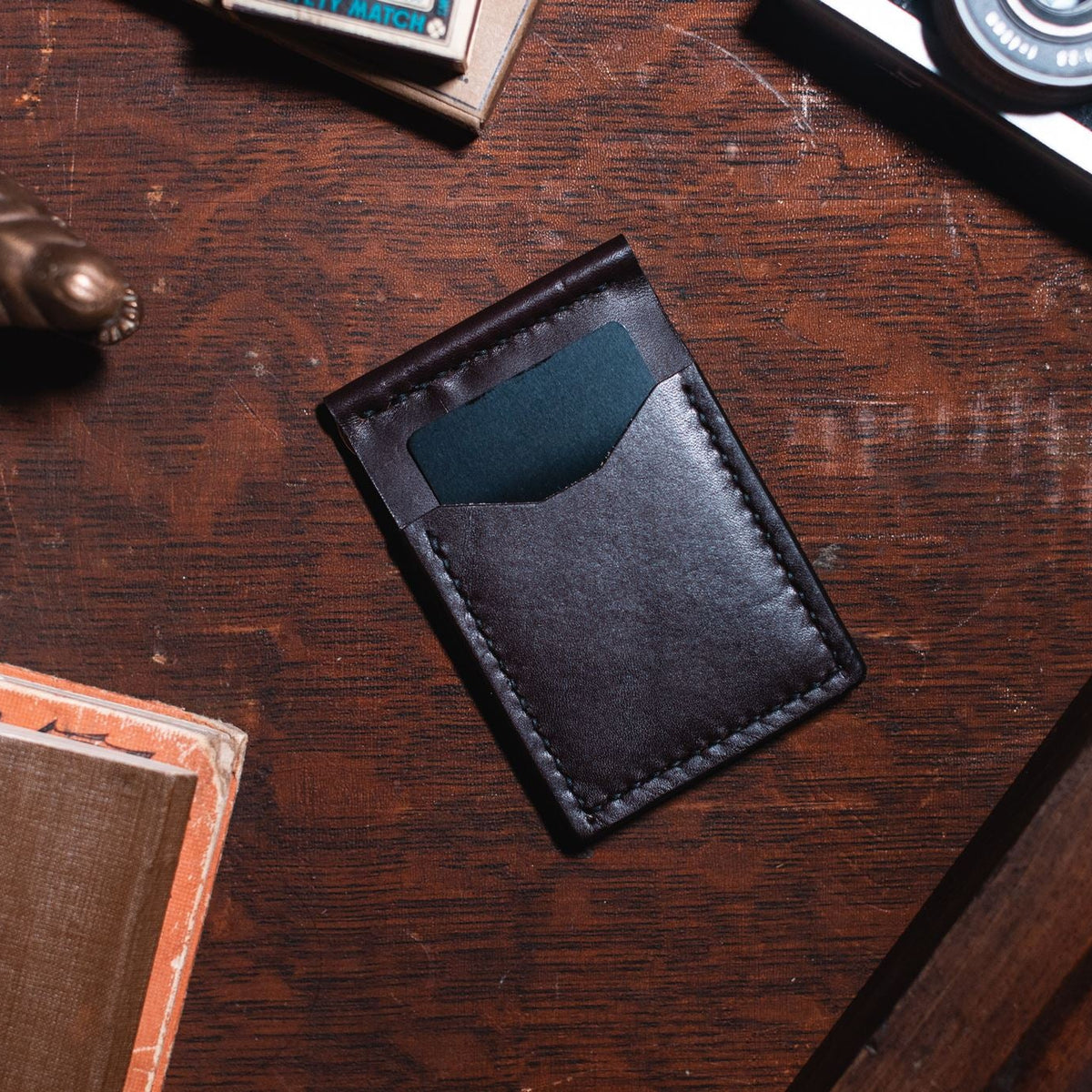 Solid Leather dark brown money clip cardholder wallet on a dark wooden desk 
