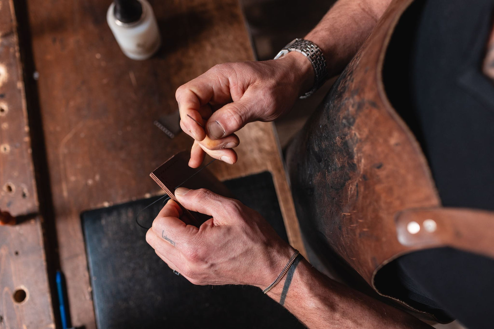 Jesse Bateson of Solid Leather Hand-stitching a full-grain leather wallet at his workbench in Peterborough Ontario Canada  