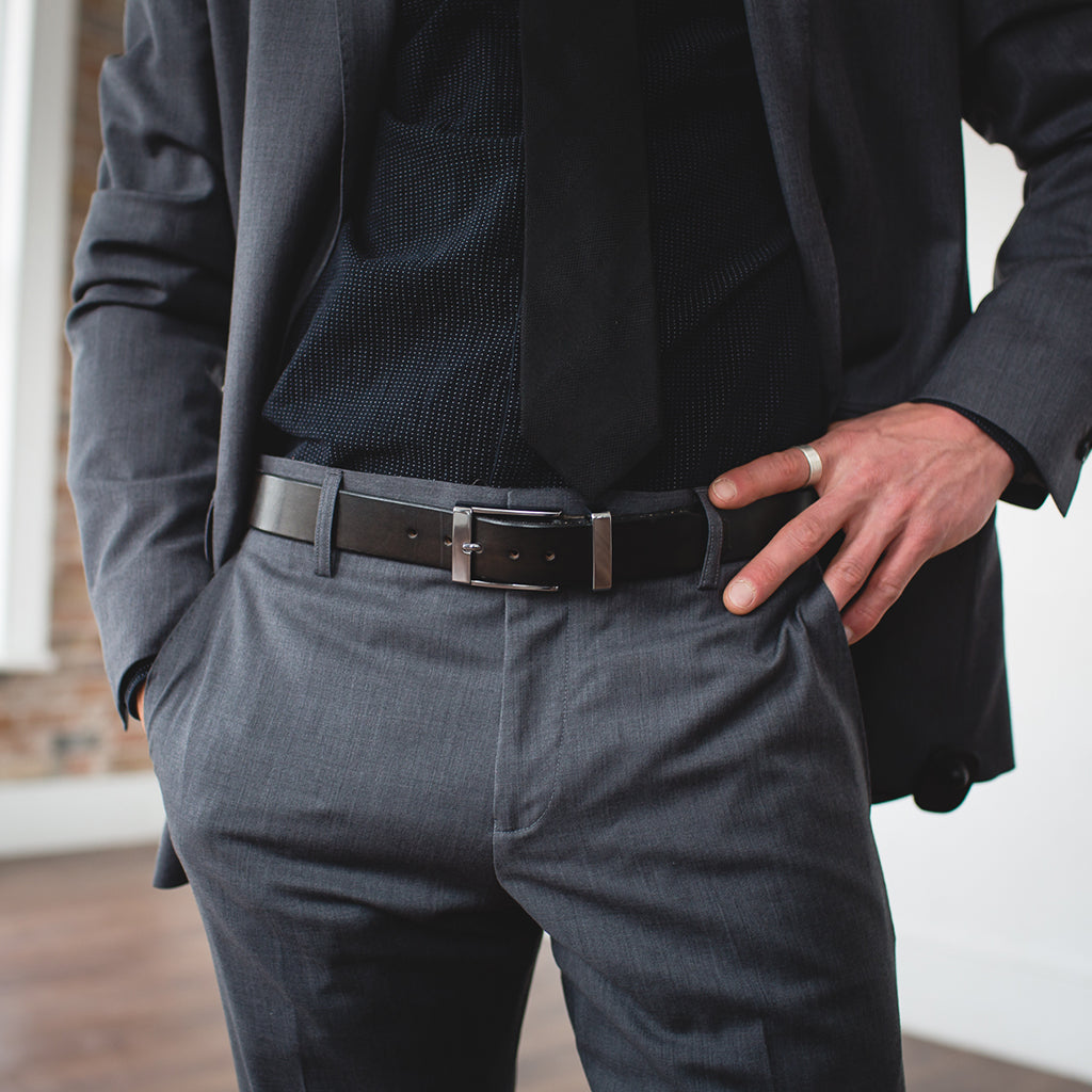 a black formal full grain leather belt with stainless steel buckle being worn on a grey suit 