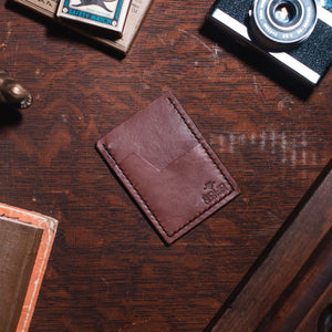 a slim minimalist cardholder wallet by Solid Leather on a dark wood desk.
