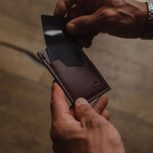 a mans hands removing a card from a Solid Leather slim wallet with blurred background