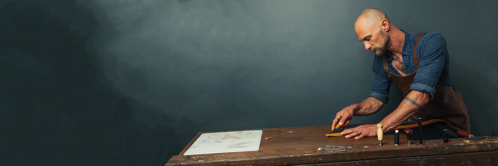 Jesse Bateson at the belt making bench trimming the end of a leather belt