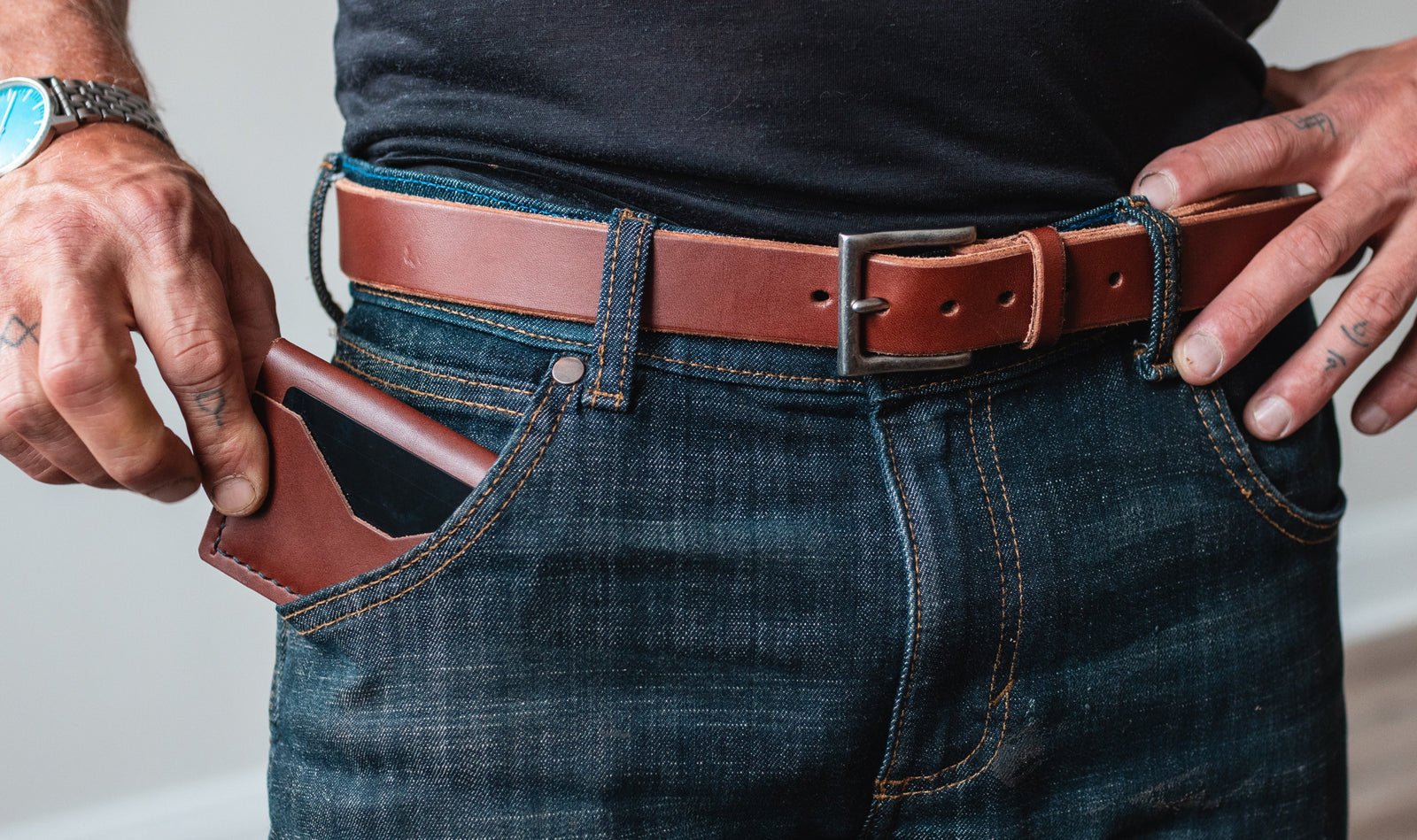 a close up shot of a full grain cognac brown leather bifold wallet with matching leather belt 