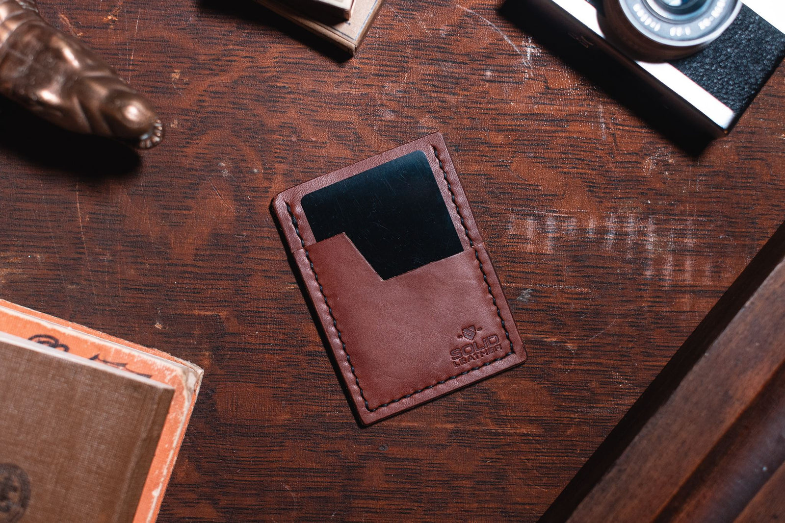 a Solid Leather slim leather wallet in cognac brown on a dark wooden desk 