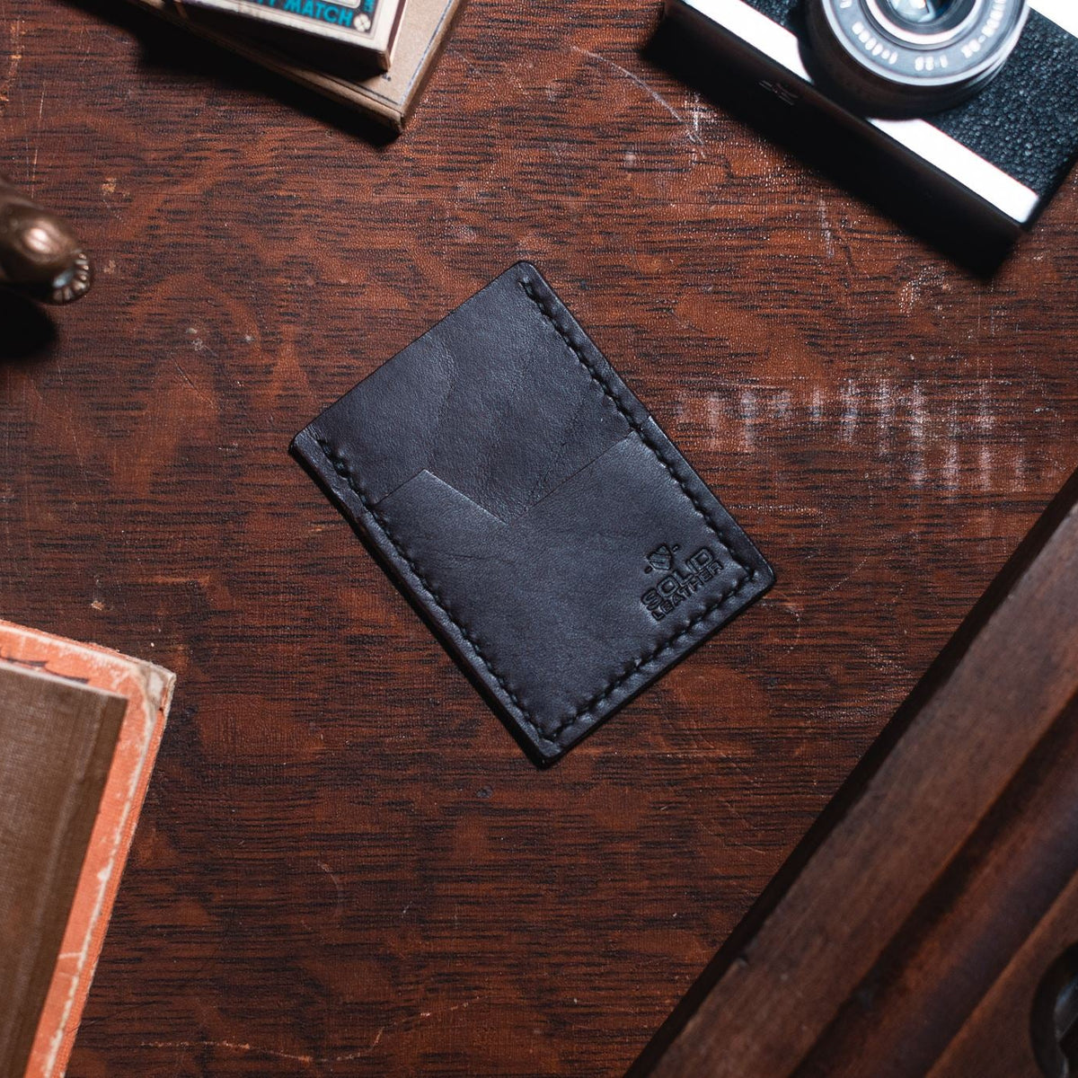 a Solid Leather dark brown cardholder wallet on a dark wood desk 