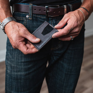 a dark brown leather cardholder wallet is shown off with a matching full-grain leather formal belt worn on  blue jeans 