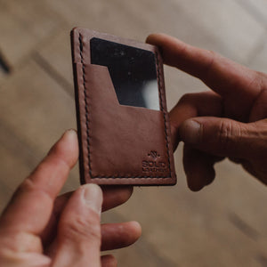 hands holding a slim Solid Leather cardholder wallet with a blurred background. 