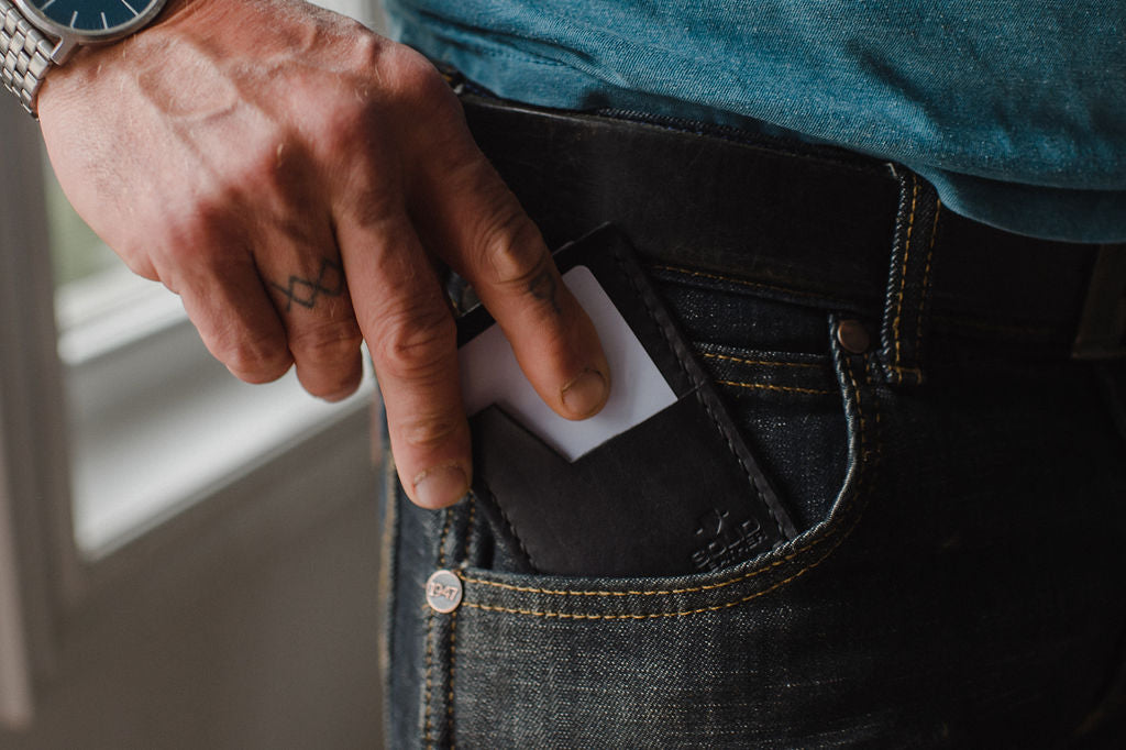 Slim cardholder wallet in black leather goingi into the front pocket of jeans 