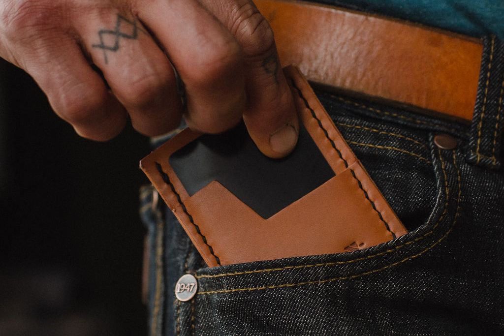 a close up shot of a tan leather cardholder wallet in the front pocket of jeans with a matching full-grain leather belt 